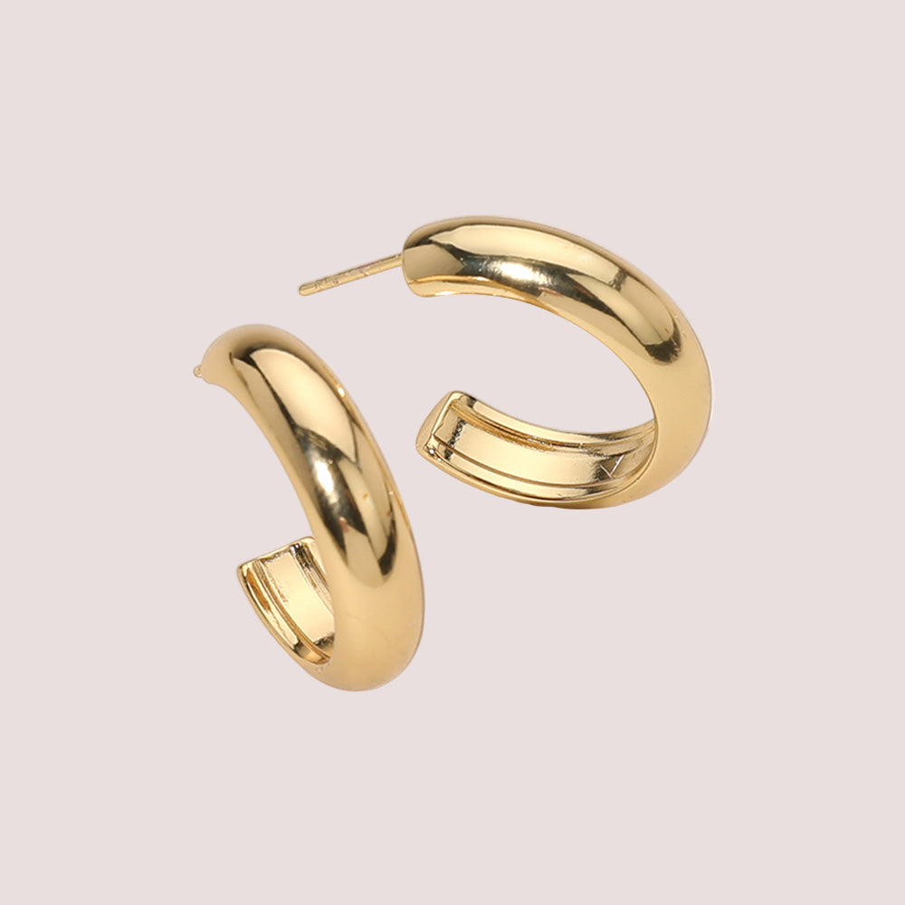 Gold hoop earrings on a light beige background