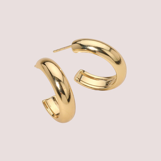 Gold hoop earrings on a light beige background